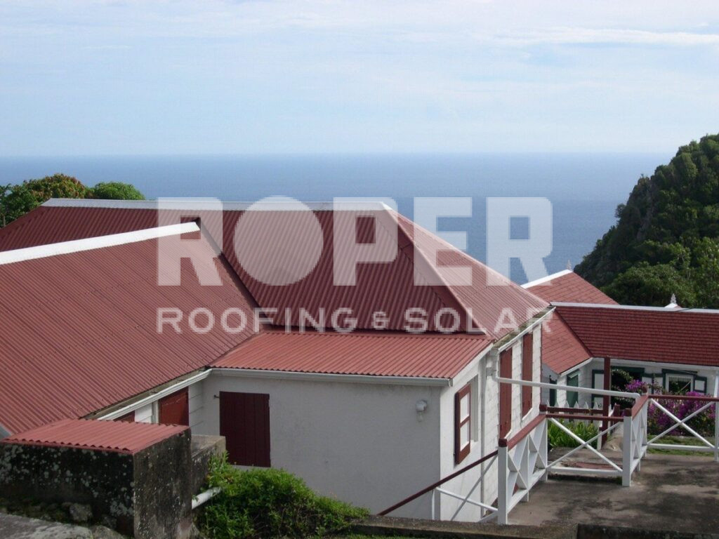 Red metal roofing on tropical coastal homes with ocean view and lush greenery