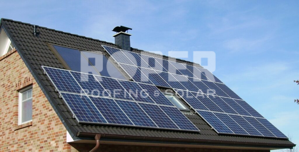 Solar panels installed on residential house roof with brick exterior and blue sky