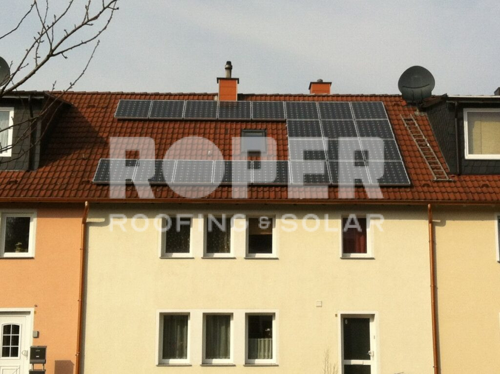 Solar panels installed on red tile roof of yellow residential house