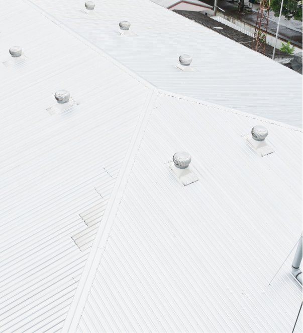 White commercial building roof with metal ventilation turbines and corrugated surface