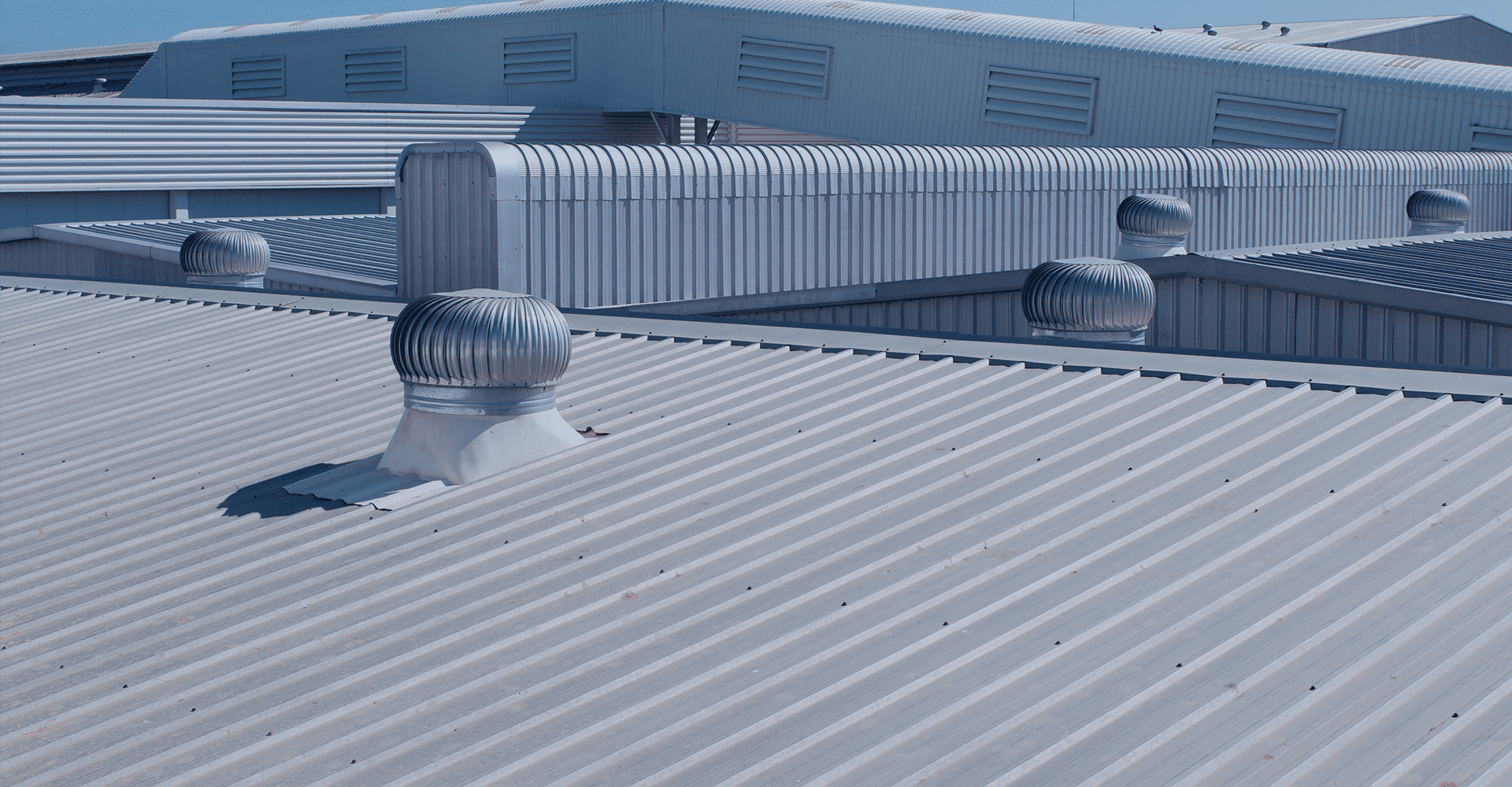 Industrial metal roof with whirlybird ventilators and corrugated buildings
