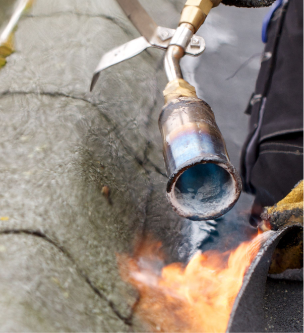 Plumber using torch to repair copper pipe with flame on concrete surface
