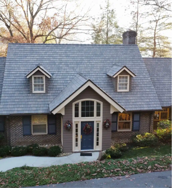 Charming brick house with blue door, dormer windows, and slate roof in autumn