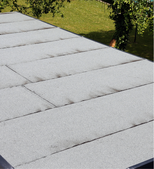 Gray concrete patio with rectangular slabs next to green lawn and trees