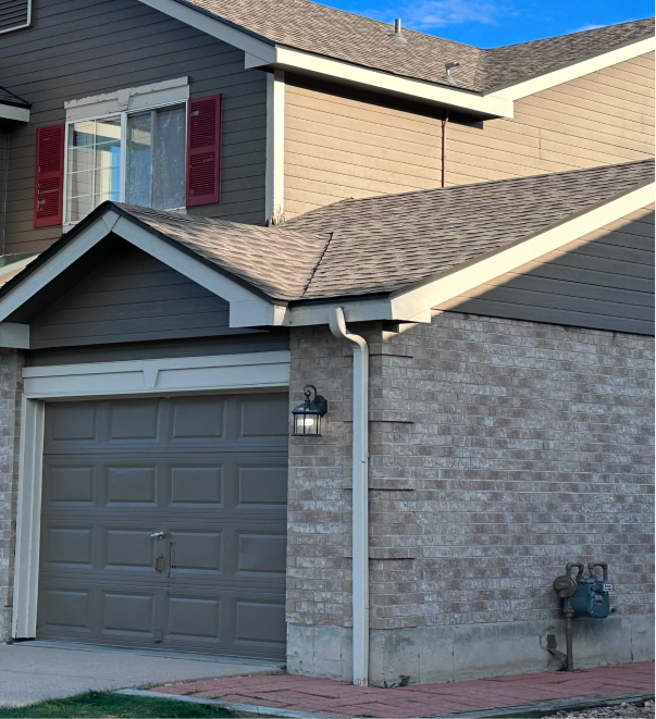 Modern two-story house with gray garage door, brick exterior, and red shutters