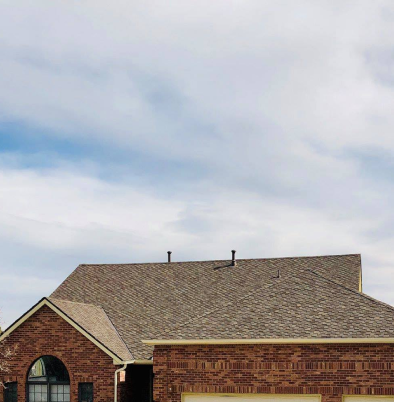 Red brick house with brown shingle roof under cloudy sky