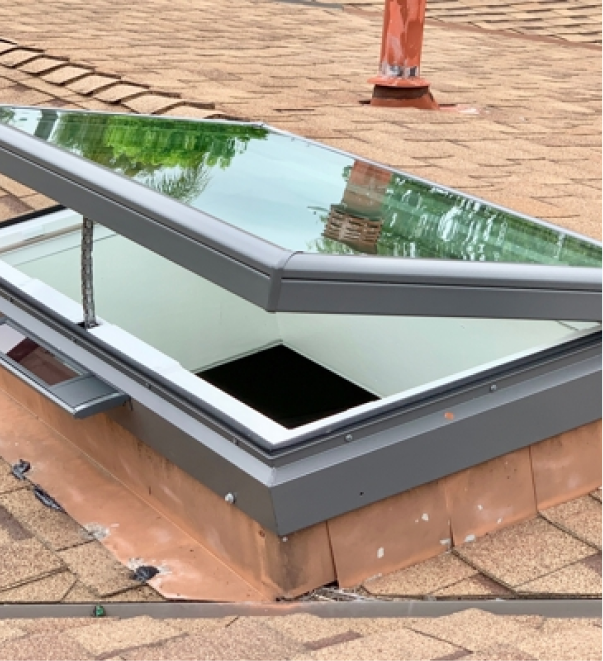 Modern glass skylight window installed on tiled roof with metal frame and reflective surface