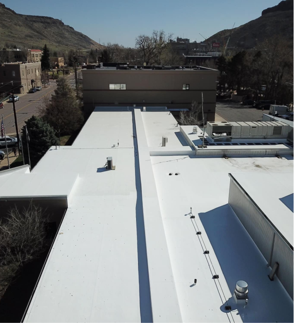 White commercial building rooftop with mountains and desert town in background