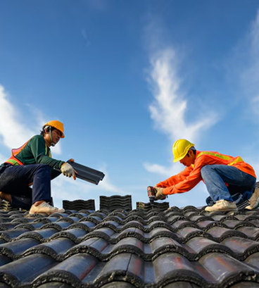 Two construction workers in hard hats installing solar panels on clay tile roof