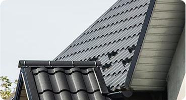 Modern house roof with dark gray tiles and metal roofing materials installation