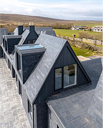 Modern dark grey house with slate roof in rural countryside setting