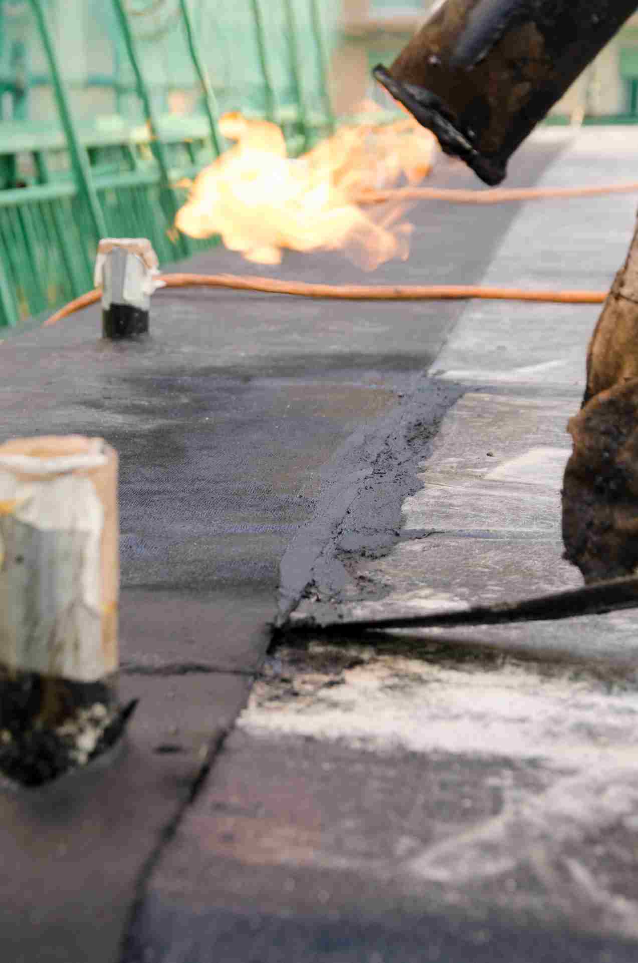 Waterproofing torch with flame applying membrane to concrete roof surface