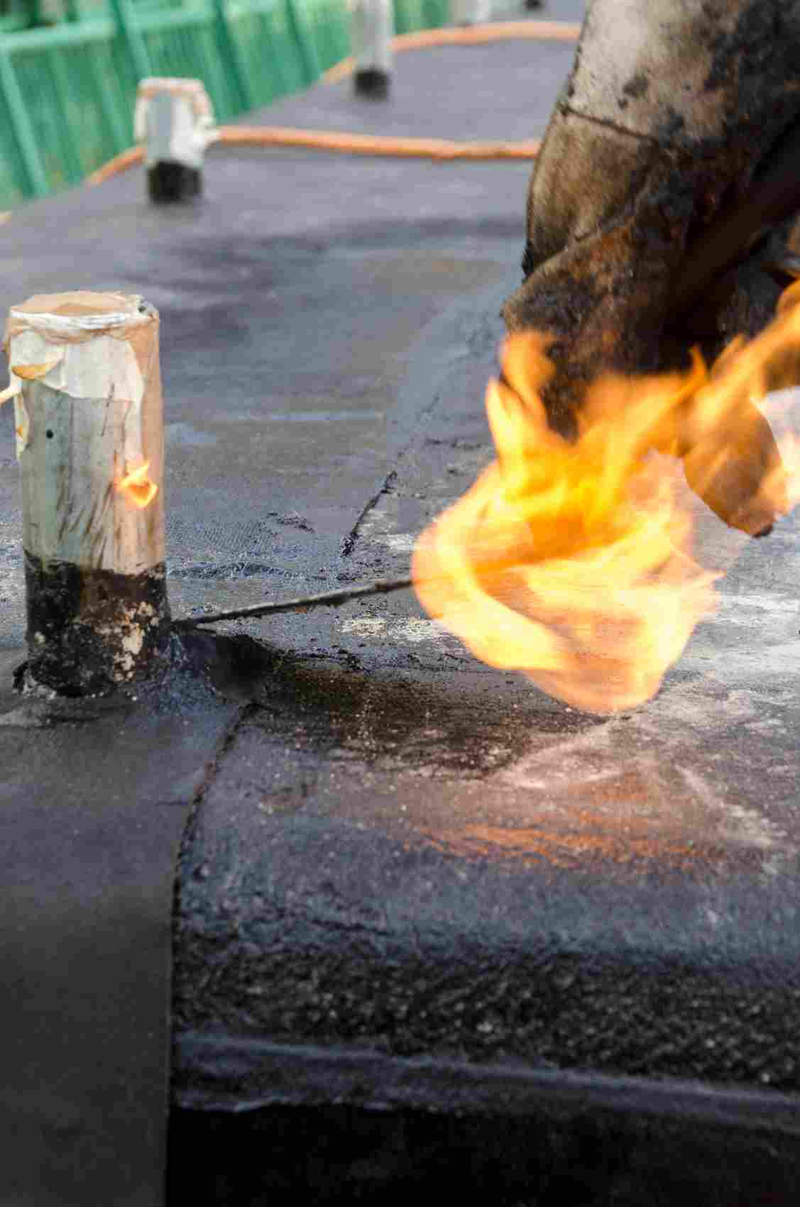 Construction worker using blowtorch flame on concrete pavement repair project