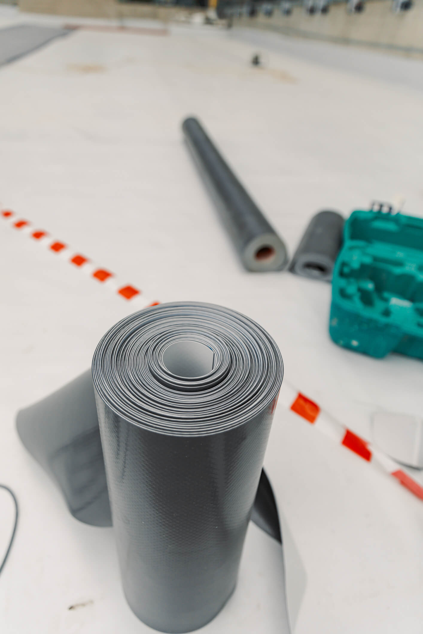 Gray rubber roll material on white table with industrial supplies and tools