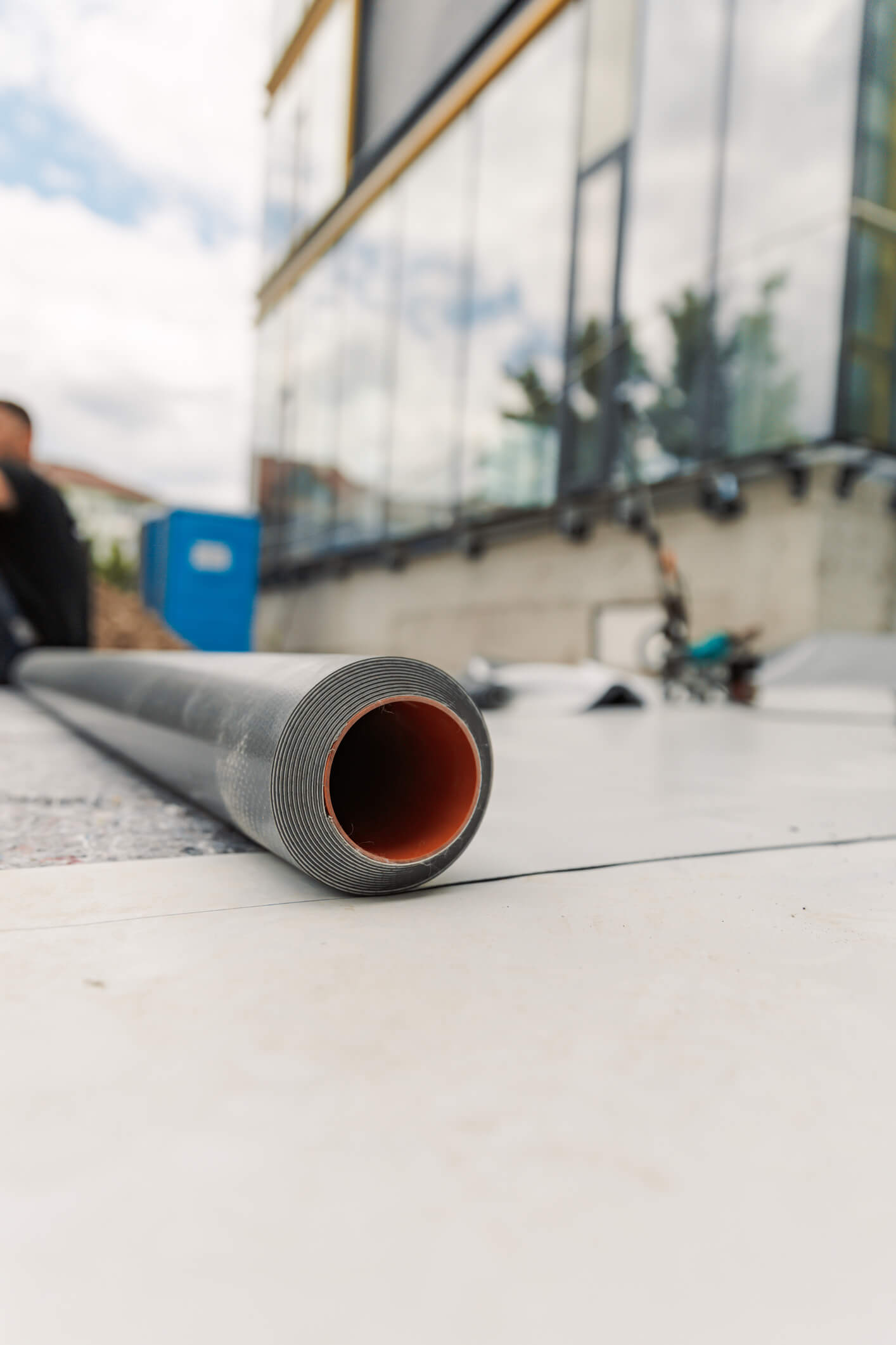 Roll of gray construction material with orange interior on white surface in workspace