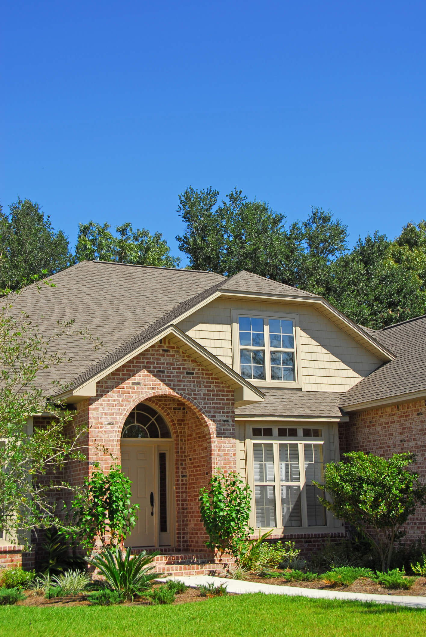 Beautiful brick and stone residential home with arched entrance and manicured lawn
