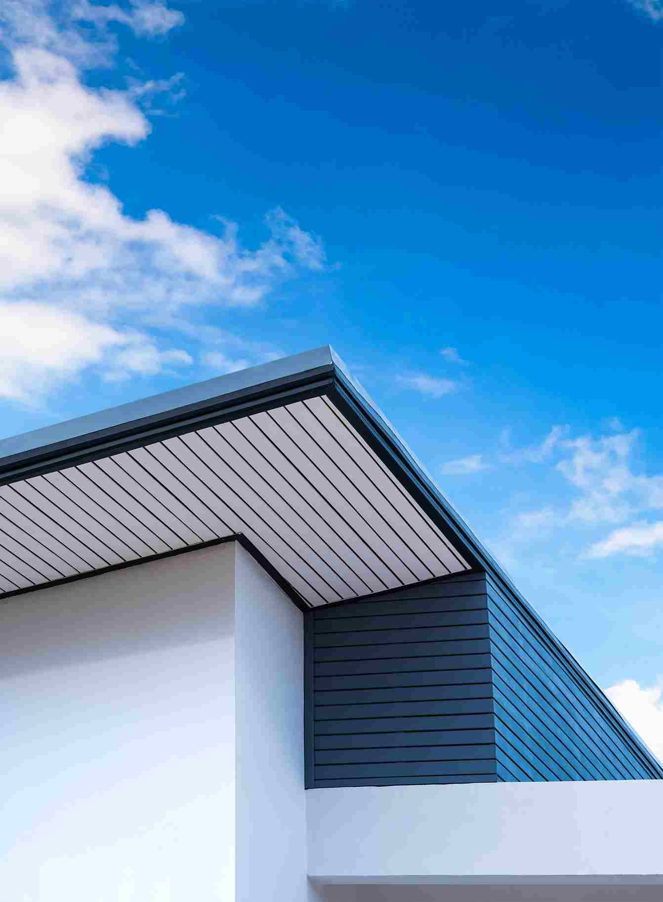 Modern house exterior with dark siding and white walls against blue sky