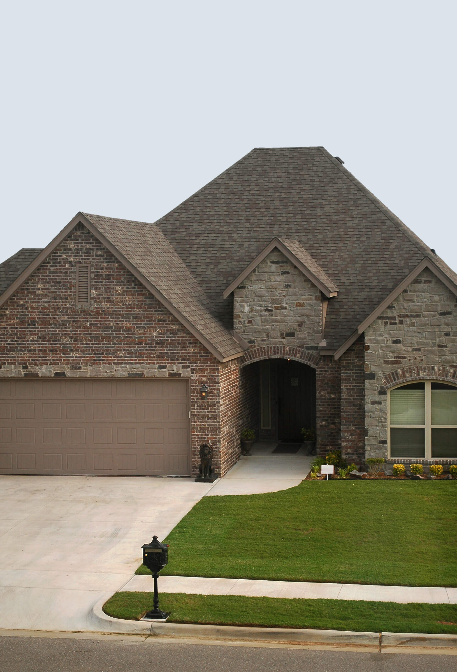 Elegant brick and stone house with arched entryway and manicured lawn