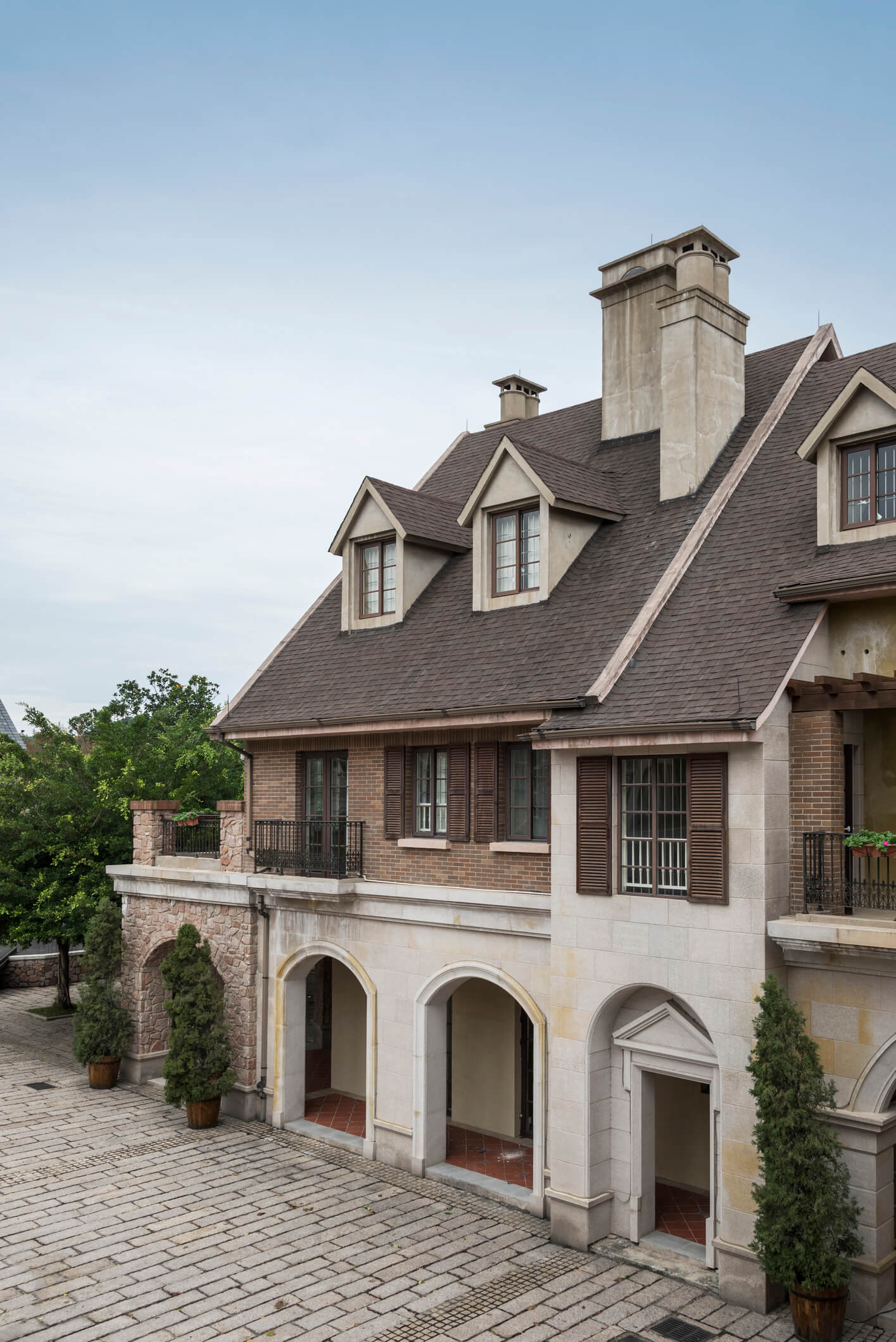 Elegant two-story brick and stone mansion with dormer windows and arched entryway