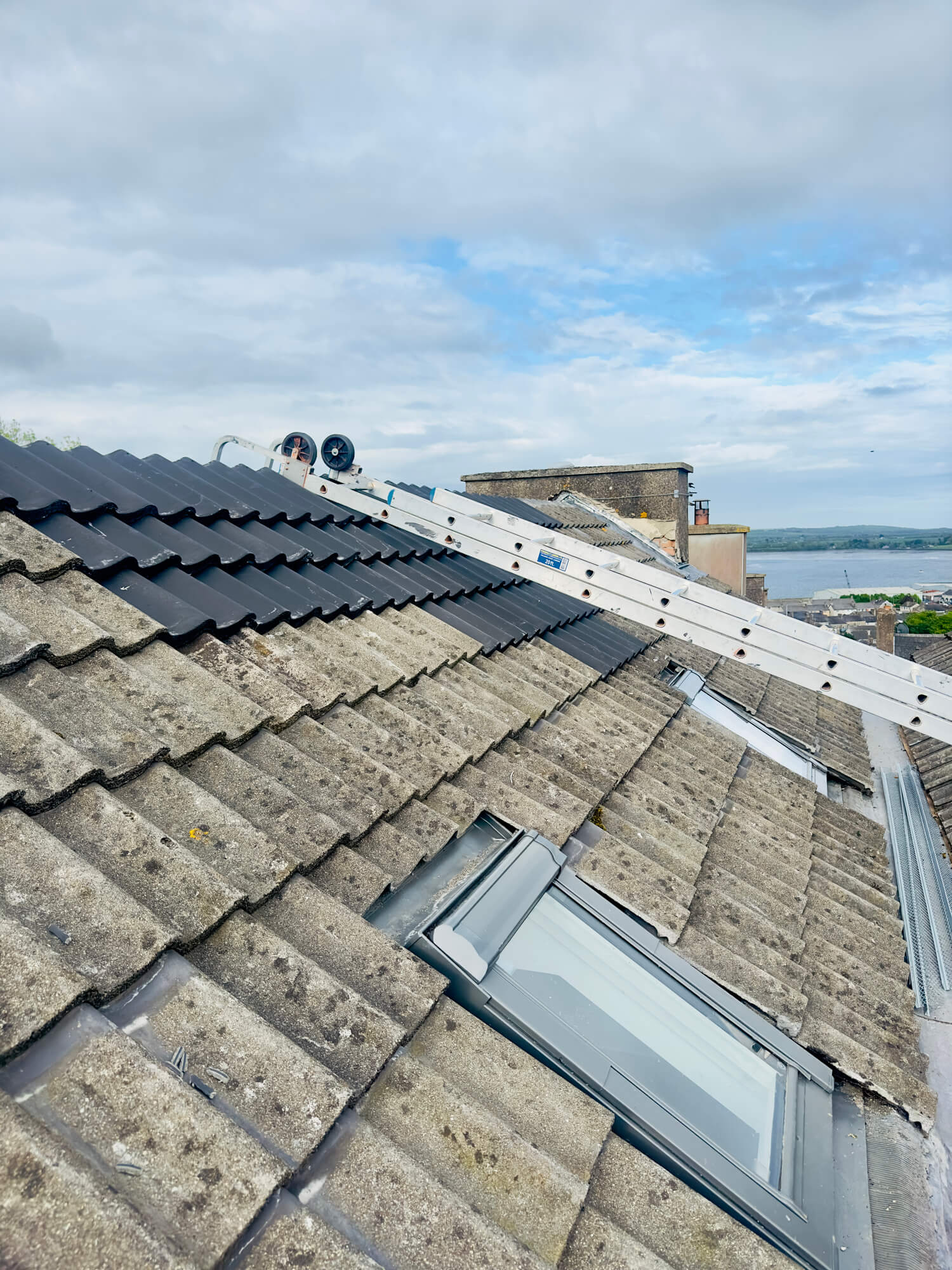 Solar panel installation on tiled roof with ladder and skylight windows