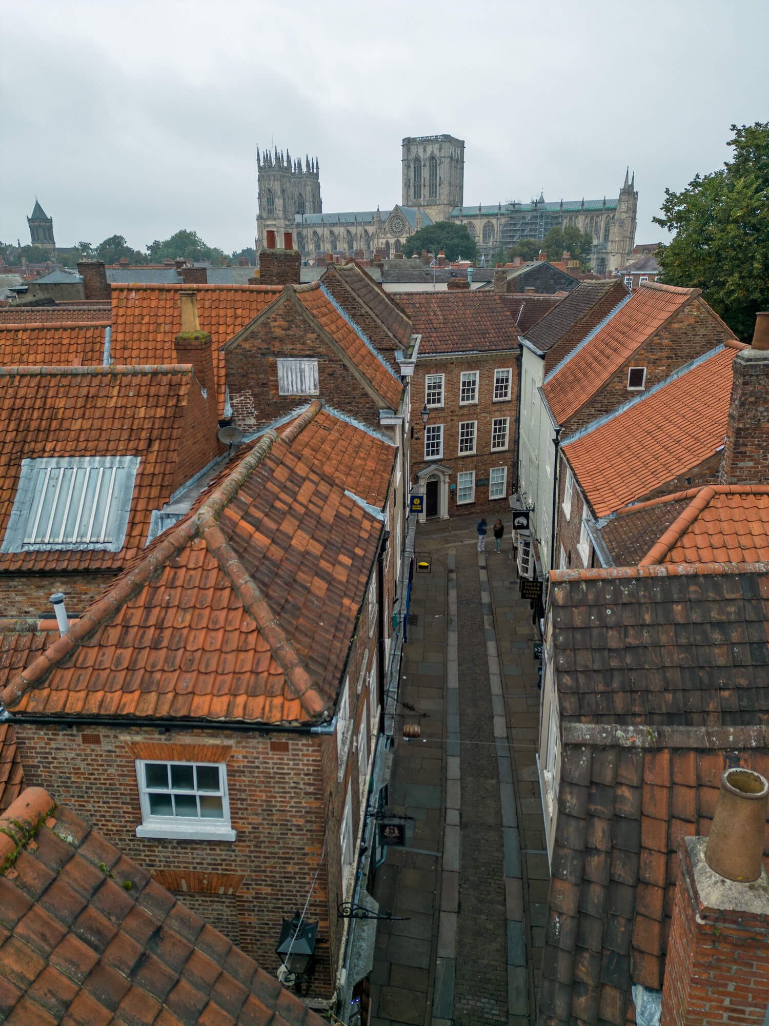 Aerial view of historic English city with red tile rooftops and Gothic cathedral