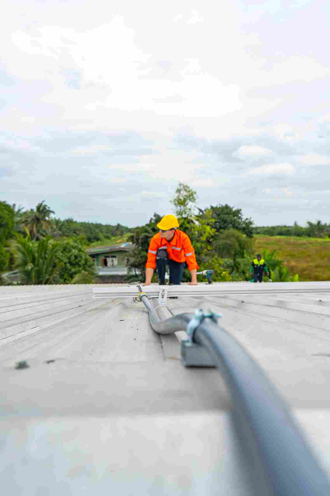 Construction worker in orange safety vest and yellow hard hat working on concrete roof