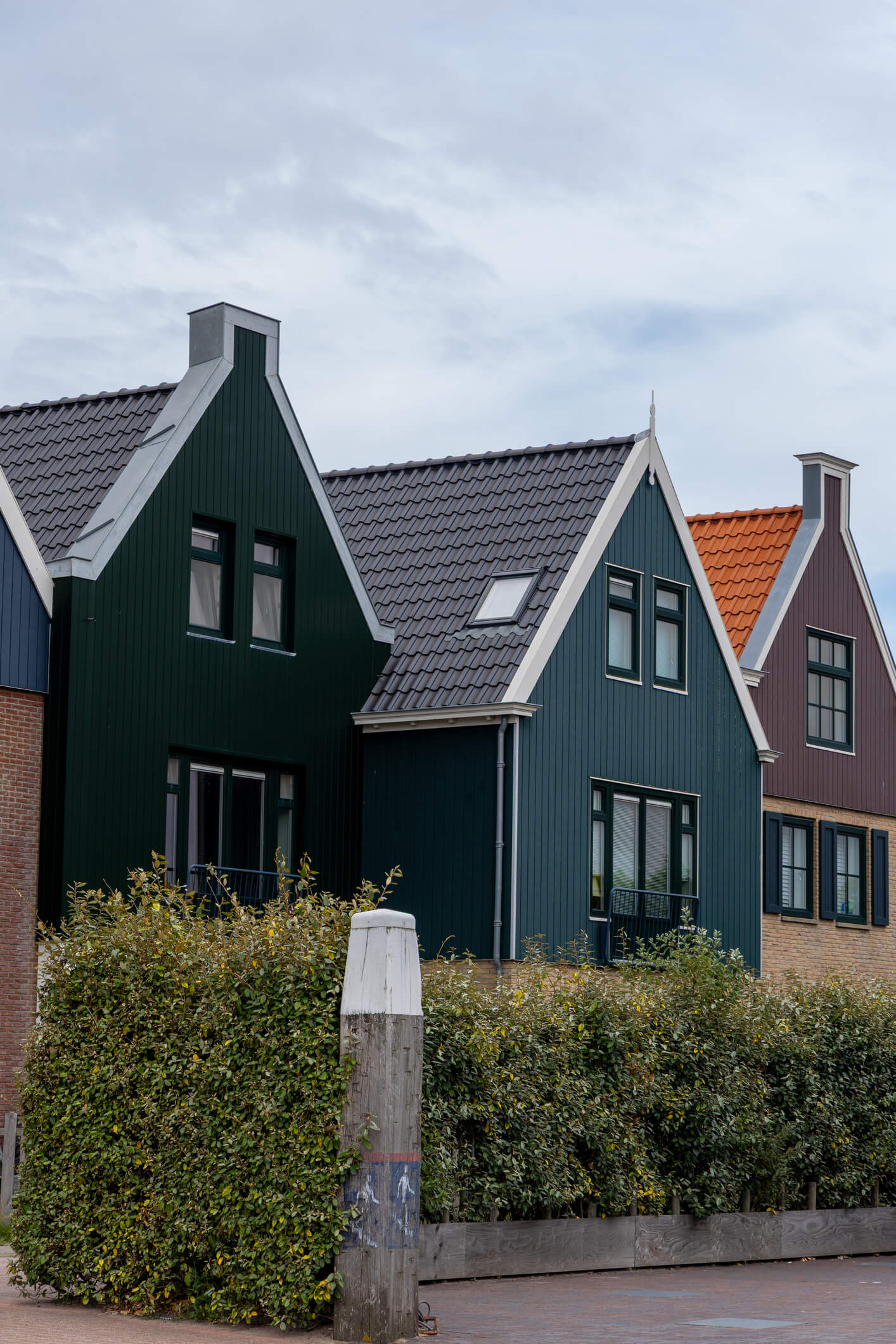 Traditional Dutch houses with green wooden facades and pitched roofs in residential neighborhood