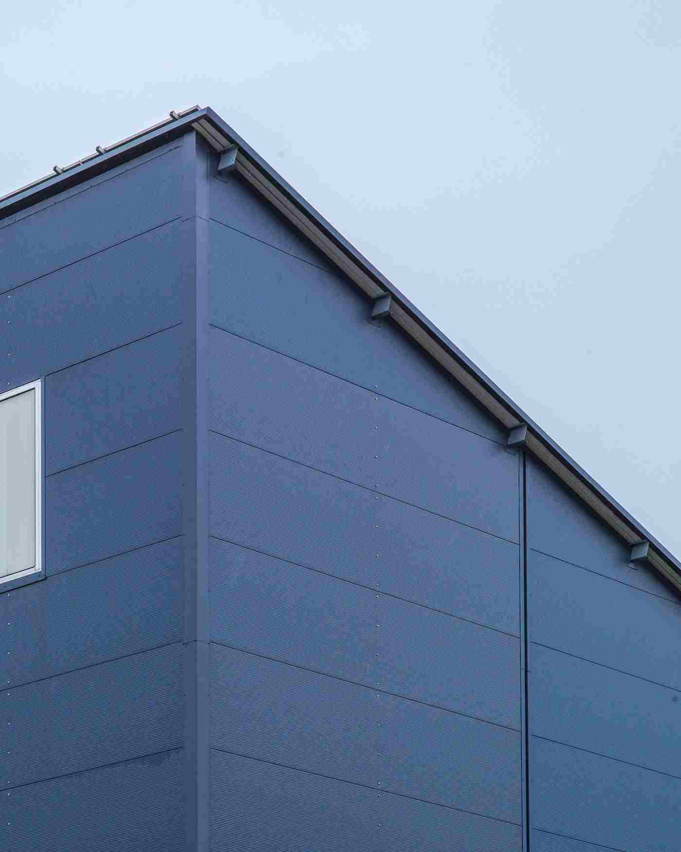 Modern blue building corner with horizontal siding against cloudy sky