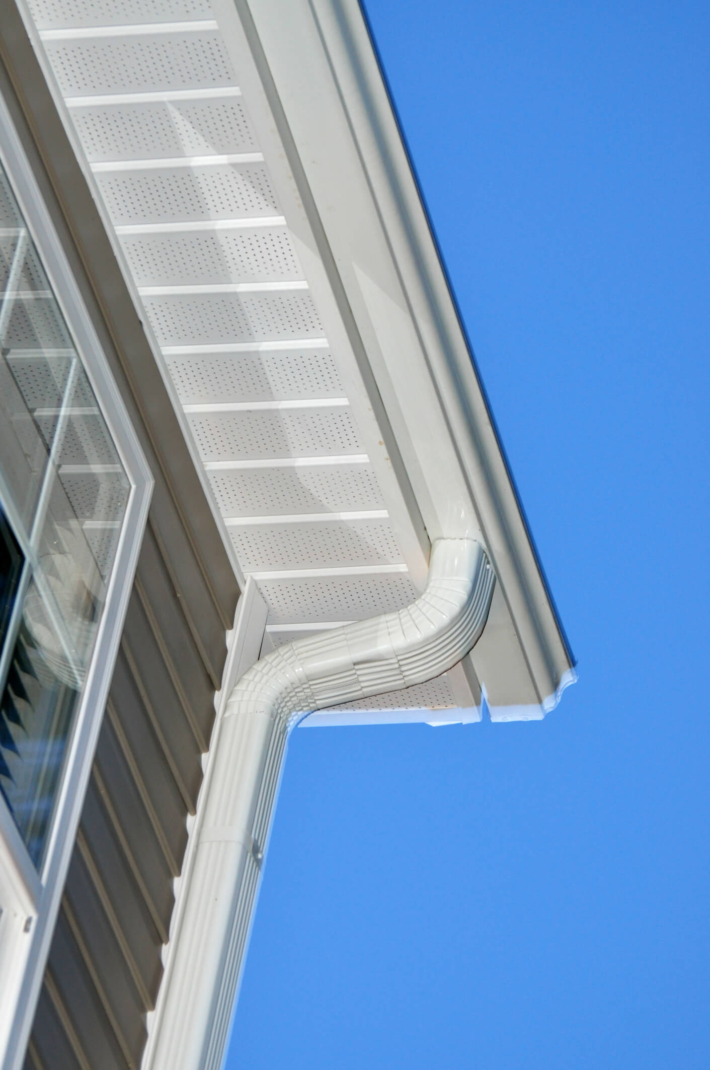 White perforated soffit and gutter system on residential building against blue sky