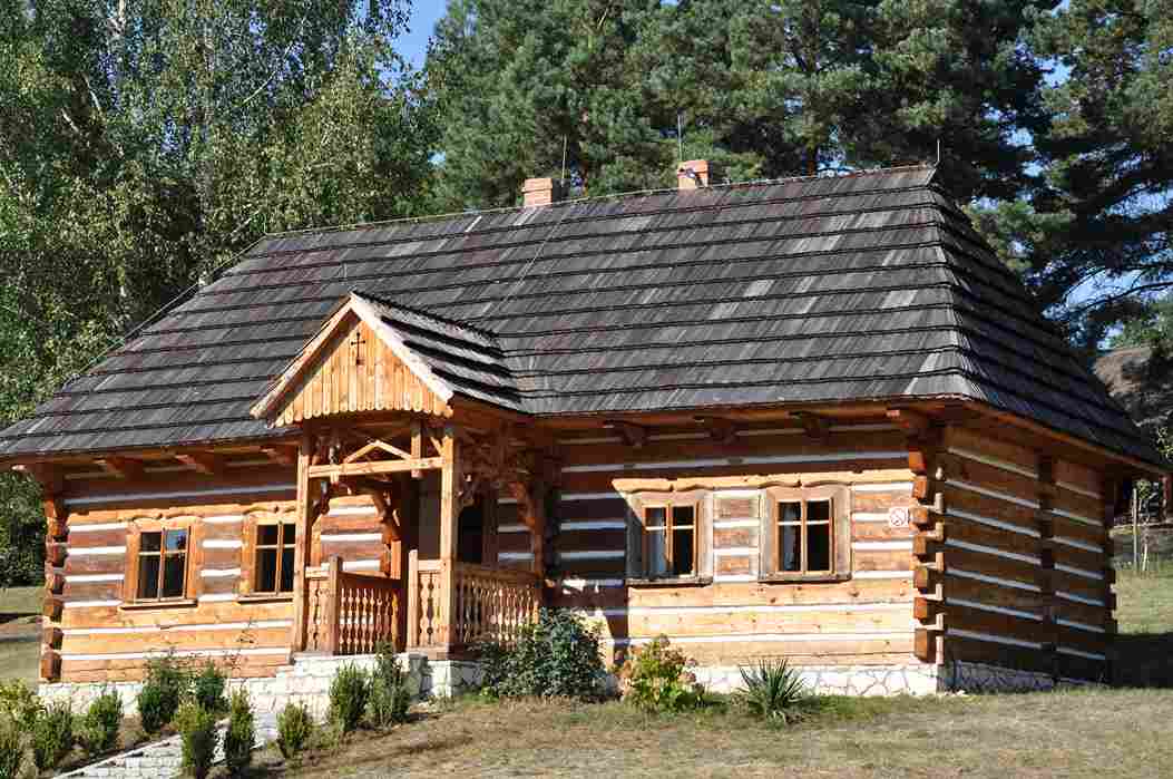 Traditional wooden log cabin with covered porch surrounded by trees