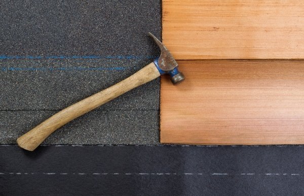 close up view of two wood shingles on roof felt with hammer