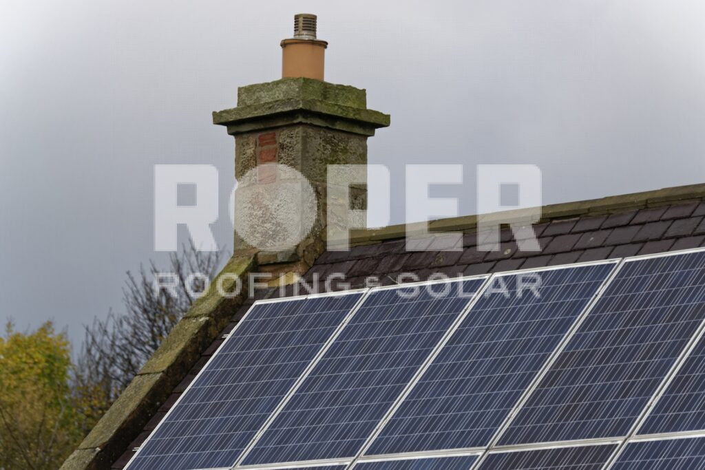 Solar panels installed on house roof with traditional stone chimney stack