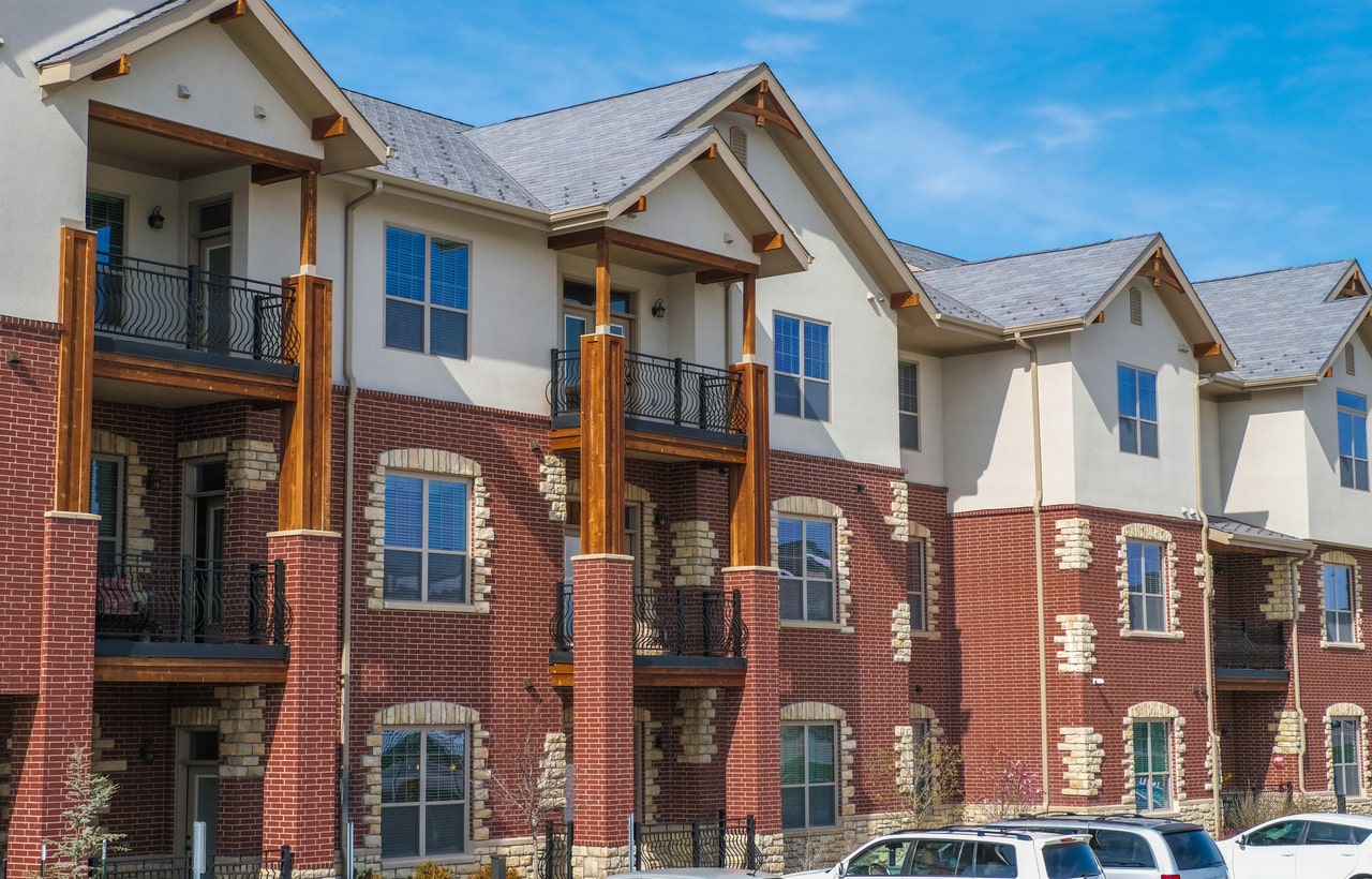 Modern brick townhouses with balconies and blue shutters under clear sky